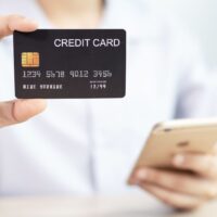クレジットカードを手に持ちながらスマートフォンを操作している様子