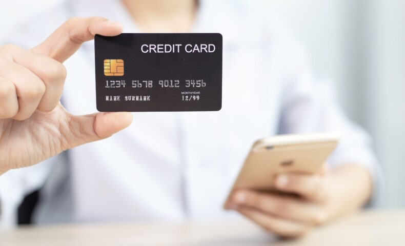 クレジットカードを手に持ちながらスマートフォンを操作している様子